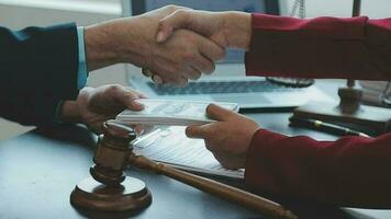 Justice and Law concept. Legal counsel presents to the client a signed contract with gavel and legal law or legal having team meeting at law firm in background video