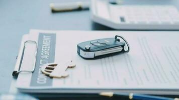 Closeup of Asian female signing car insurance document or lease paper contract or agreement. Buying or selling new or used vehicle with car keys on table. video