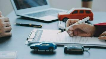 Closeup of Asian female signing car insurance document or lease paper contract or agreement. Buying or selling new or used vehicle with car keys on table. video