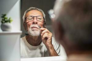 A senior man plucks his nose hair photo