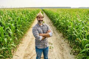 orgulloso granjero es en pie en su creciente maíz campo foto