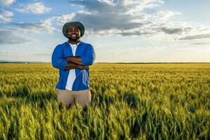 afro granjero en pie en un trigo campo foto