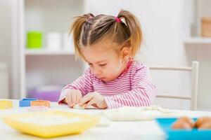 un joven niña haciendo galletas foto