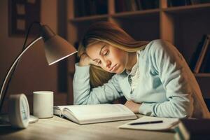 Young blonde woman studying at night photo