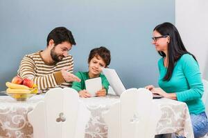 Parents are teaching their son to use the laptop photo