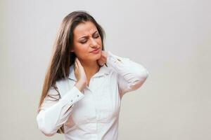 A woman in a white shirt with neck pain photo