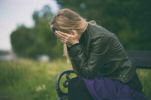 A young woman is upset and crying outdoors photo