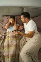 A young couple lying in bed after an argument photo