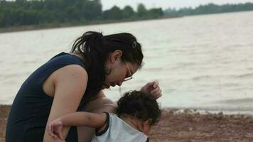 famille content, mère et bébé Faire Extérieur Activités sur le rive de une Lac à le coucher du soleil dans été. video