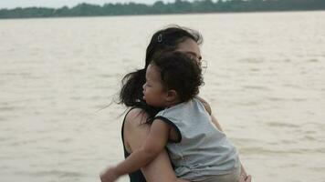 Family happy, Mother and baby doing outdoor activities on the shore of a lake at sunset in summer. video