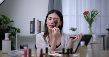 Footage of Beautiful asian woman blogger showing how to make up and use cosmetics. Influencer lady lives streaming cosmetics product reviews in the home studio. Influencer and cosmetics concepts. video