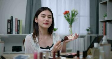 Footage of Beautiful asian woman blogger showing how to make up and use cosmetics. Influencer lady lives streaming cosmetics product reviews in the home studio. Influencer and cosmetics concepts. video