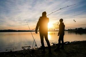 Father and son are fishing on sunny winter day photo