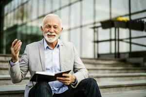 A senior businessman writing in a notebook photo