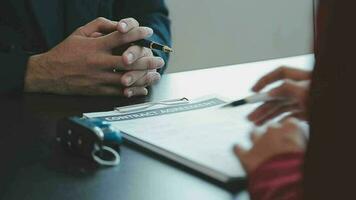 Closeup of Asian female signing car insurance document or lease paper contract or agreement. Buying or selling new or used vehicle with car keys on table. video