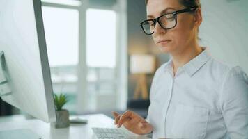 mulher com óculos digitando em uma computador teclado. conceito do controlo remoto trabalhos video