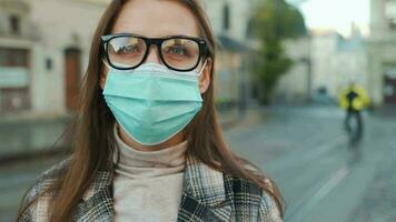 Pandemic protection of the Covid-19 coronavirus. Portrait of a woman in a coat, glasses and a protective medical mask. Glasses fog up from breath. Virus protection video