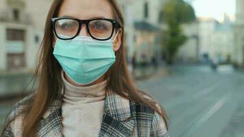 pandemisch bescherming van de covid-19 coronavirus. portret van een vrouw in een jas, bril en een beschermend medisch masker. bril mist omhoog van adem. virus bescherming video