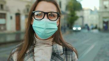 Pandemic protection of the Covid-19 coronavirus. Portrait of a woman in a coat, glasses and a protective medical mask. Glasses fog up from breath. Virus protection video