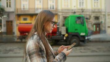 Woman walking down an old street and using smartphone video