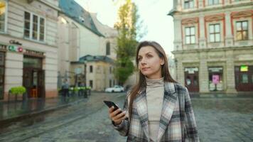 Frau Gehen Nieder ein alt Straße, mit Smartphone und nehmen ein Foto video