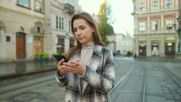 vrouw wandelen naar beneden een oud straat, gebruik makend van smartphone en nemen een foto video
