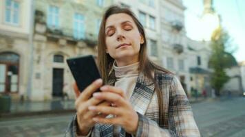 kvinna gående ner ett gammal gata, använder sig av smartphone och tar en Foto video