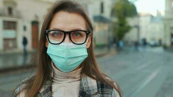 Pandemic protection of the Covid-19 coronavirus. Portrait of a woman in a coat, glasses and a protective medical mask. Glasses fog up from breath. Virus protection video