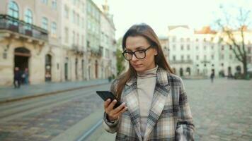 donna a piedi giù un vecchio strada e utilizzando smartphone video