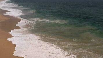 volador terminado el playa. gigante olas espumoso y salpicaduras en el Oceano desde un parte superior ángulo video
