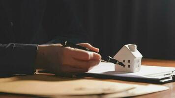 agente de bienes raíces que presenta y consulta al cliente para la toma de decisiones firmar un acuerdo de formulario de seguro, modelo de hogar, sobre oferta de préstamo hipotecario y seguro de hogar. video