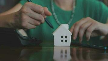 agent de courtage immobilier présentant et consultant au client pour la prise de décision signant un accord de formulaire d'assurance, modèle de maison, concernant l'offre de prêt hypothécaire et l'assurance habitation. video