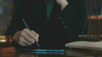 Justice and law concept.Male judge in a courtroom with the gavel, working with, computer and docking keyboard, eyeglasses, on table in morning light video