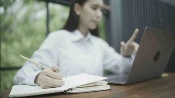 vrouw kantoor arbeider zittend buiten van de kantoor gebruik een notitieboekje naar werk en schrijven naar beneden informatie in een notebook. video