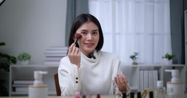 Footage of Beautiful asian woman blogger showing how to make up and use cosmetics. Influencer lady lives streaming cosmetics product reviews in the home studio. Influencer and cosmetics concepts. video