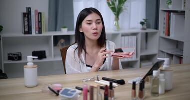 Footage of Beautiful asian woman blogger showing how to make up and use cosmetics. Influencer lady lives streaming cosmetics product reviews in the home studio. Influencer and cosmetics concepts. video