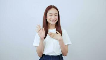 linda joven asiático estudiante niña levanta su mano y pone su palma en su pecho. video