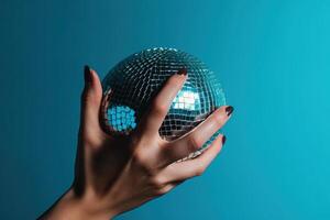 Shiny disco ball in a woman hand isolated on a bright blue background. nightlife, and celebration inspired idea. illustration photo