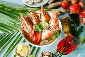 Shrimp soup on seafood soup bowl with thai herb and spices, Thai Food Tom Yum Kung, Hot and sour spicy shrimps prawns soup  curry lemon lime galangal red chili straw mushroom on table food photo