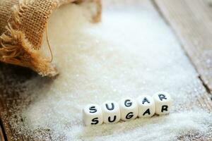 blanco azúcar para comida y dulces postre caramelo montón de dulce azúcar cristalino granulado, azúcar en saco y de madera antecedentes foto