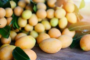 Marian plum fruit and leaves in plate on wooden background, tropical fruit Name in Thailand Sweet Yellow Marian Plum Maprang Plango or Mayong chid photo