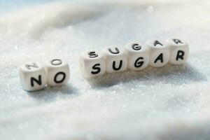 no sugar text blocks with white sugar on wooden background, suggesting dieting and eat less sugar for health photo