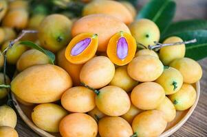 mariano ciruela Fruta y hojas en plato en de madera fondo, tropical Fruta nombre en Tailandia dulce amarillo mariano ciruela maprang plango o mayong chid foto