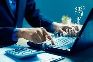 Businessman planning 2023 business growth on desk with virtual hologram chart graph. Calculate income and profit on investments and an increase in the indicators of positive growth, Return on Stocks photo