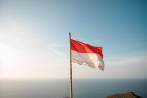 Indonesia nacional bandera ondulación en el azul cielo en el Oceano antecedentes. rojo y blanco bandera con nubes ai generado foto