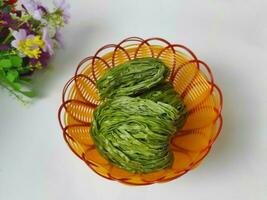 Dried green spinach noodles in small basket isolated on white background. photo