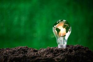 Concept of renewable energy innovation and green earth. Sustainable clean energy sources. Environmental protection, Idea sustainable energy sources. Light bulb put on soil on green nature background. photo
