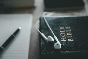 Christian online technology concept. Earphones over the holy bible with digital smartphone, Online live church for sunday service. Holy bible book and online study. photo