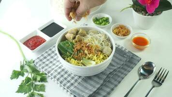 polpetta, nel Indonesia conosciuto come bakso o basso. servito con tagliatelle verdure chili salsa nel un' ciotola su bianca sfondo con mano. vicino su superiore Visualizza piatto posare video