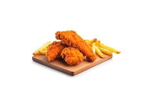 Crispy delicious fried chicken and french fries on a rectangular wooden board isolated on white background. photo